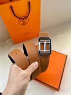 Tan Hermes belt coiled with silver H buckle and punched holes
