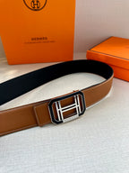 Tan Hermes belt with wide silver-and-black H buckle