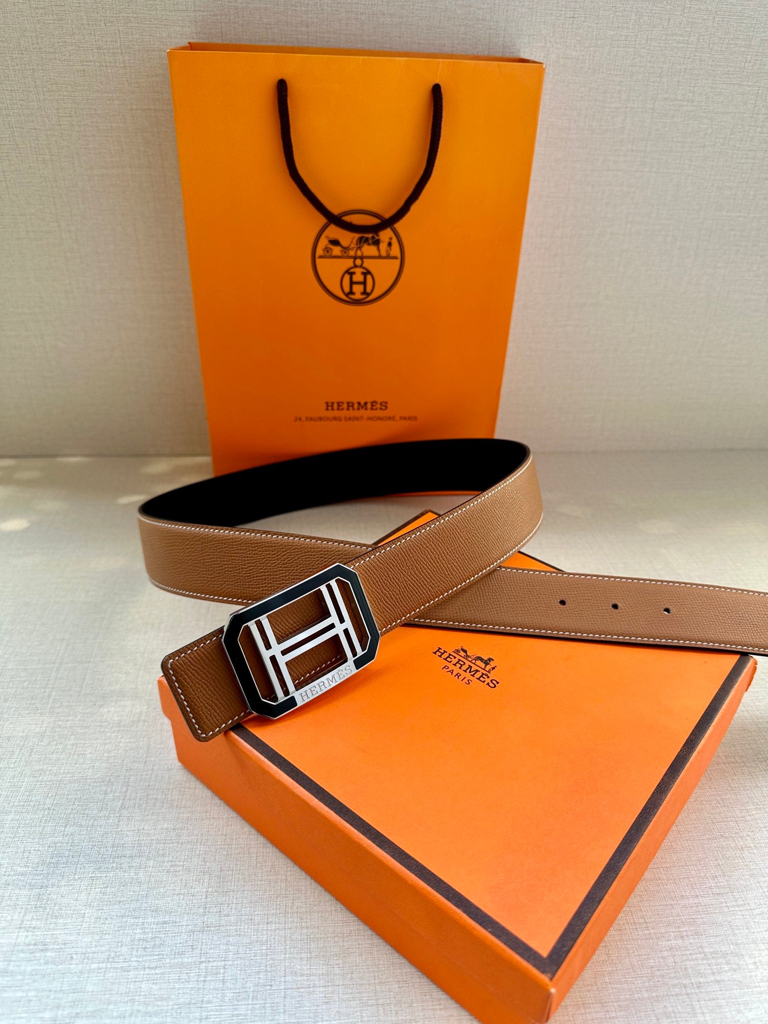 Tan Hermes belt with silver H buckle and perforated strap holes