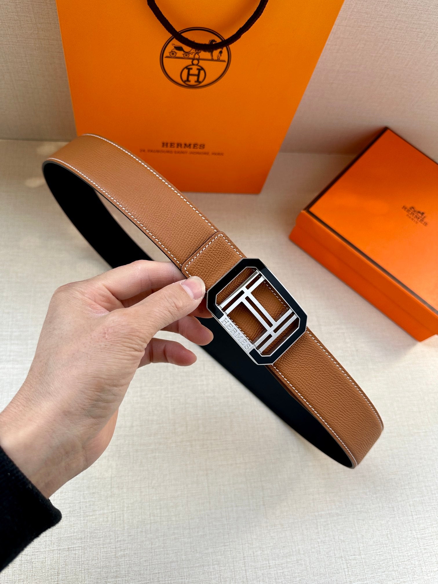 Tan Hermes belt with black underside and silver H buckle