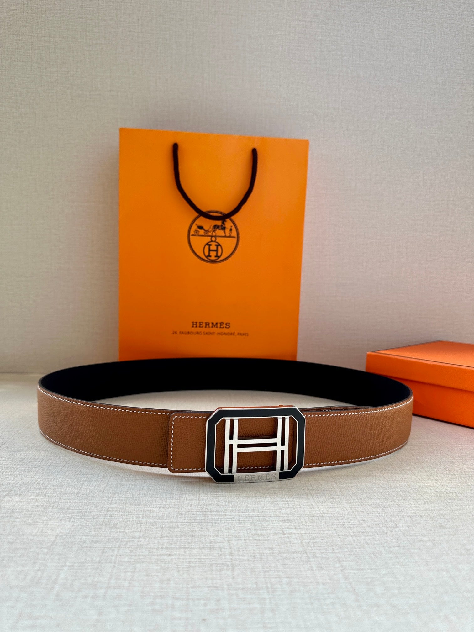 Tan Hermes belt with black lining and silver H buckle
