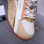 Versace sneaker close-up: white knit upper, orange piping, gold zipper trim