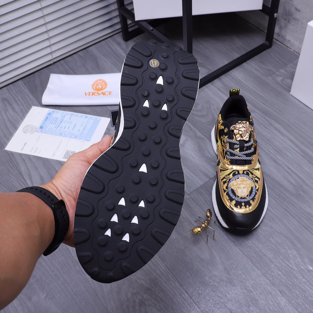 Versace luxury shoes, sole view black sneakers with textured tread and gold patterned uppers