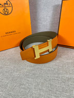 Two-tone leather belt with wide orange strap, olive underside, and silver H buckle