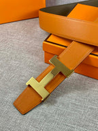 Two-tone leather belt with orange strap, olive backing, and H buckle detail