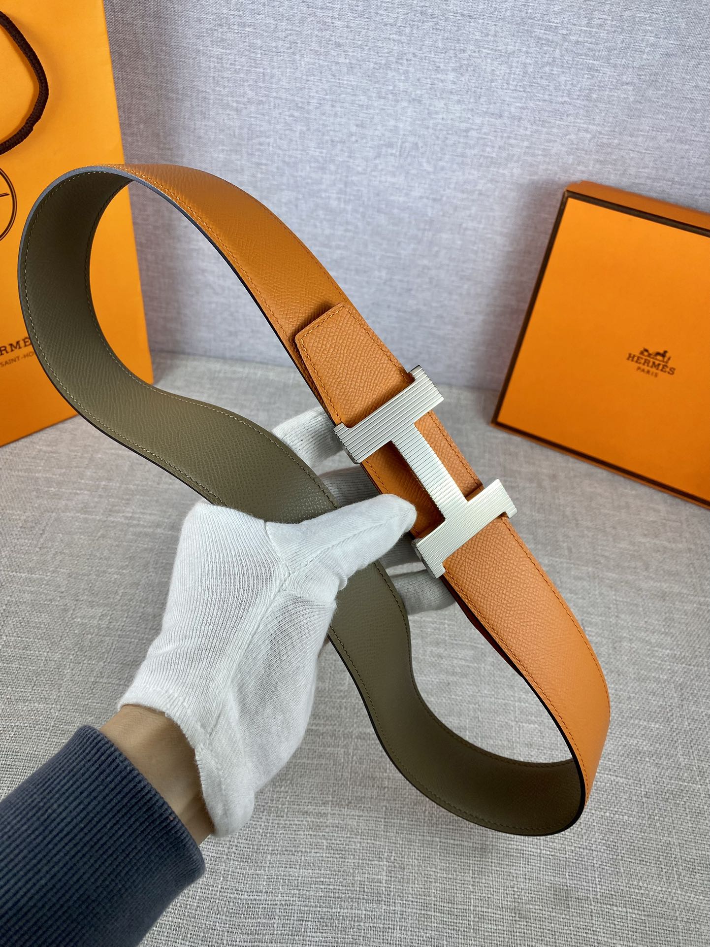 Two-tone leather belt with orange strap and olive strap, ribbed H buckle detail