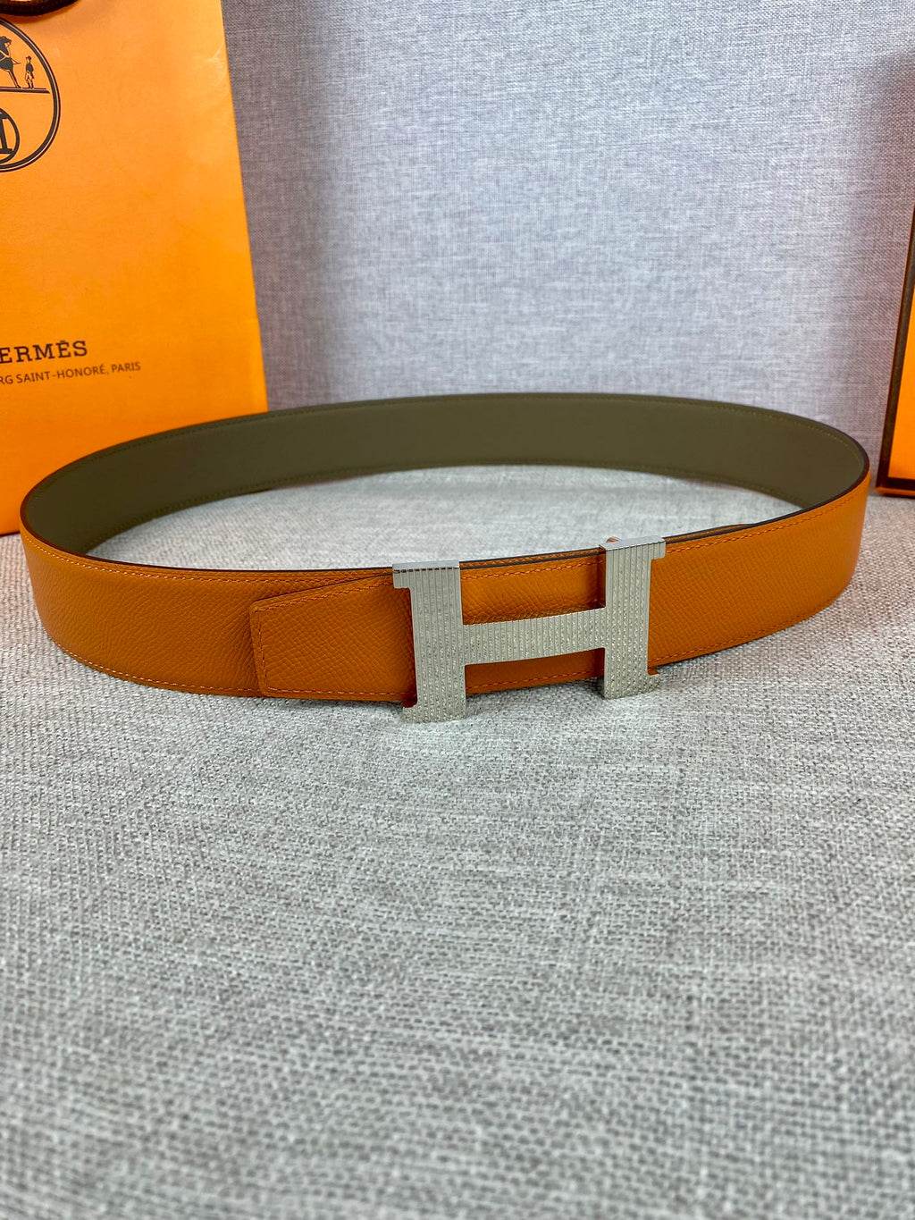 Orange leather belt with wide H buckle and textured finish
