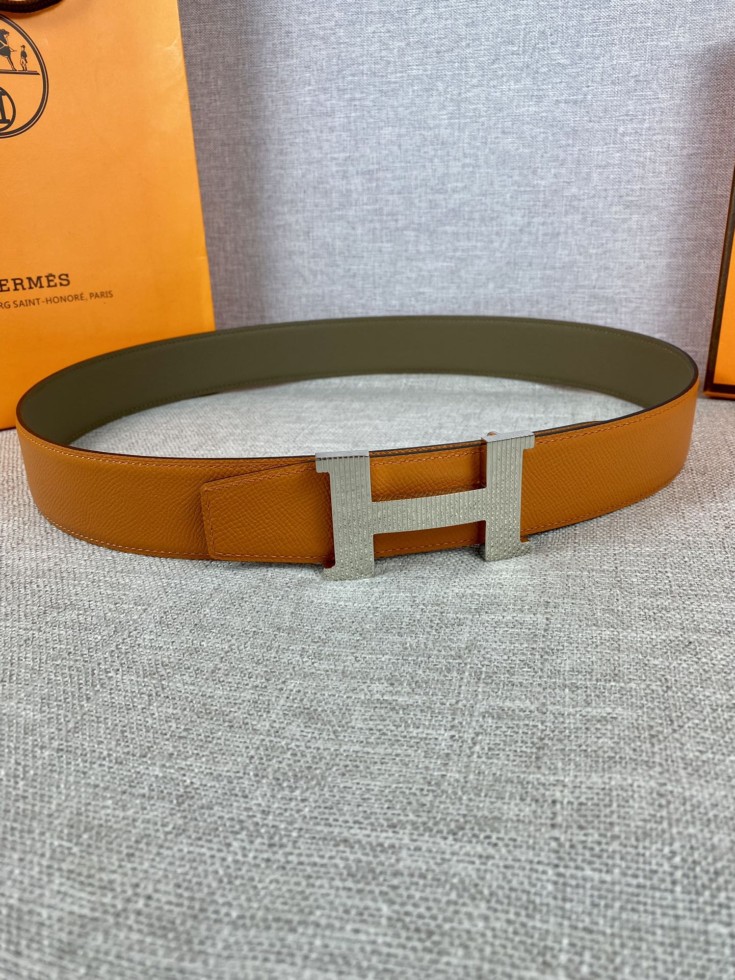 Orange leather belt with wide H buckle and textured finish