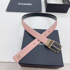 Chanel belt laid across box: dark strap, pink underside, Chanel logo, gold chain buckle.