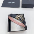 Chanel belt with dark leather strap, gold buckle, and chain-link detail, pink underside.