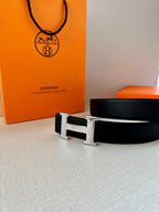 Dark leather belt with metallic rectangular buckle and H motif
