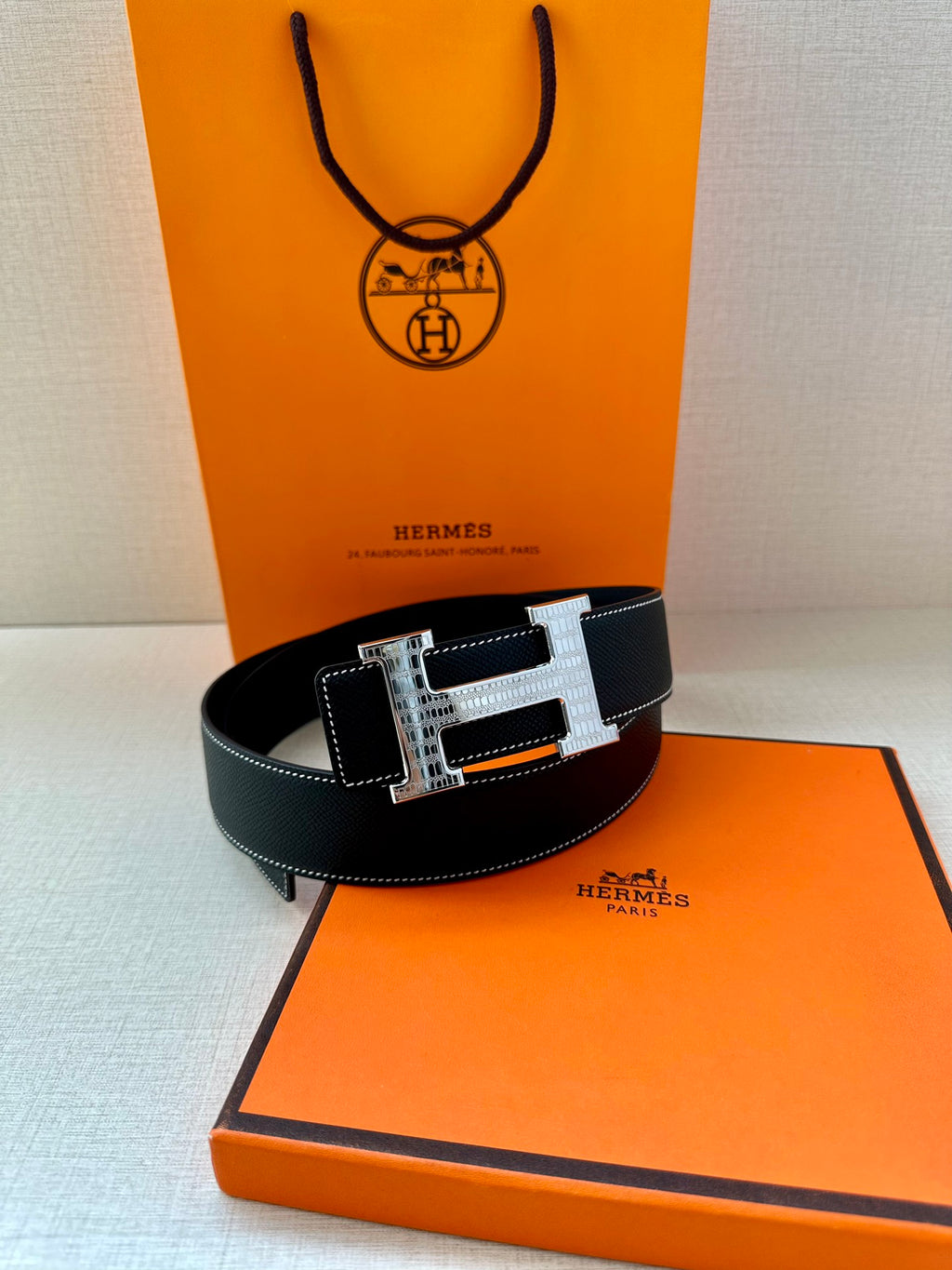 Hermes leather belt with silver-and-gold H buckle, centered closure, belt holes visible