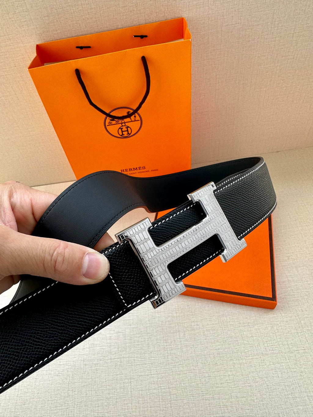 Hermes leather belt with H buckle, silver metal frame and gold-toned center, close-up