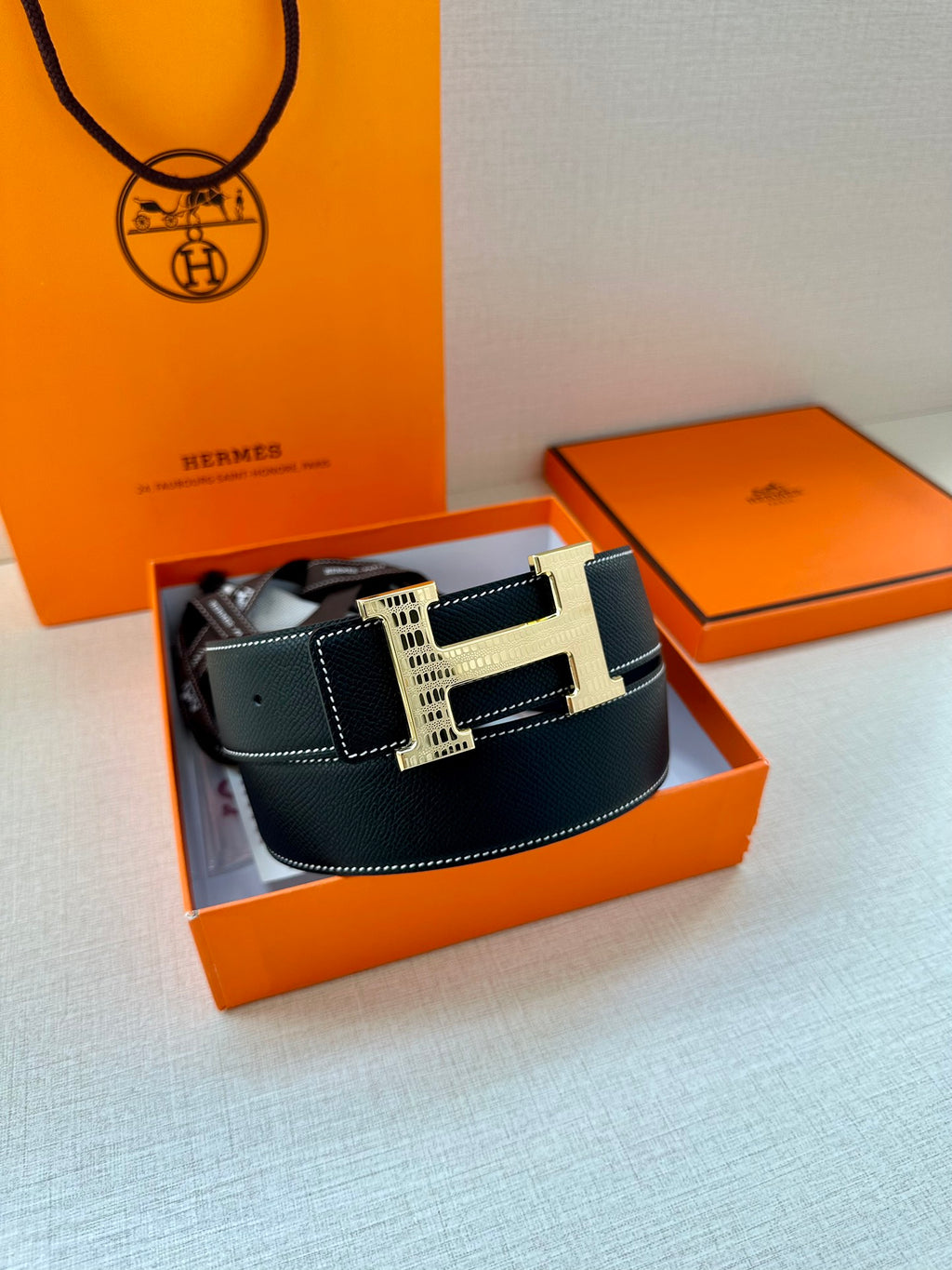 Hermes leather belt with H buckle and keeper strap, laid in an open box