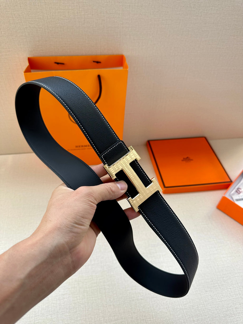 Hermes leather belt with silver-and-gold H buckle, long belt end and stitching visible