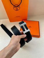 Hermes leather belt with silver-and-gold H buckle detail, hand-held angle view