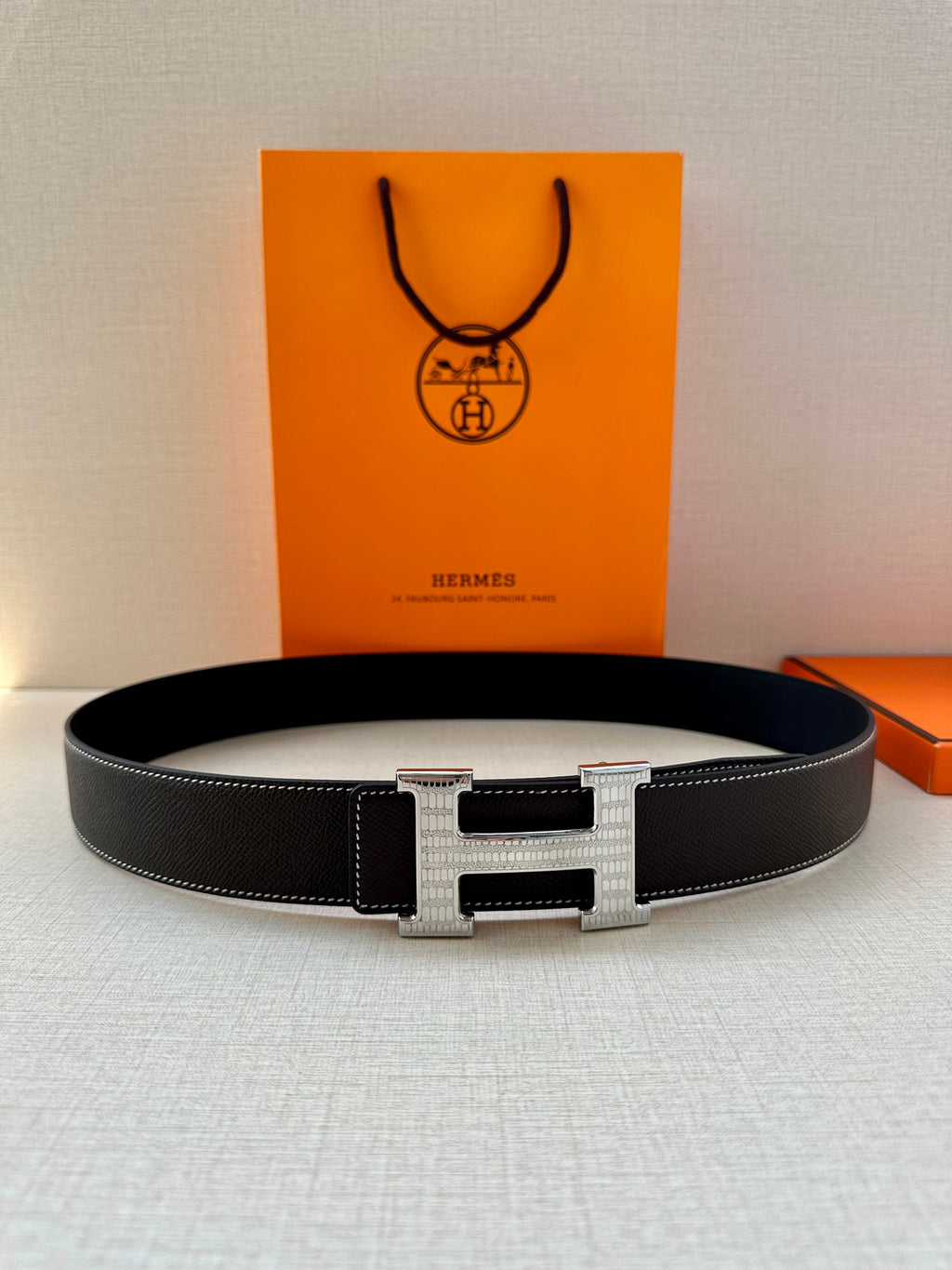Dark leather belt with silver-tone buckle, flat laying view