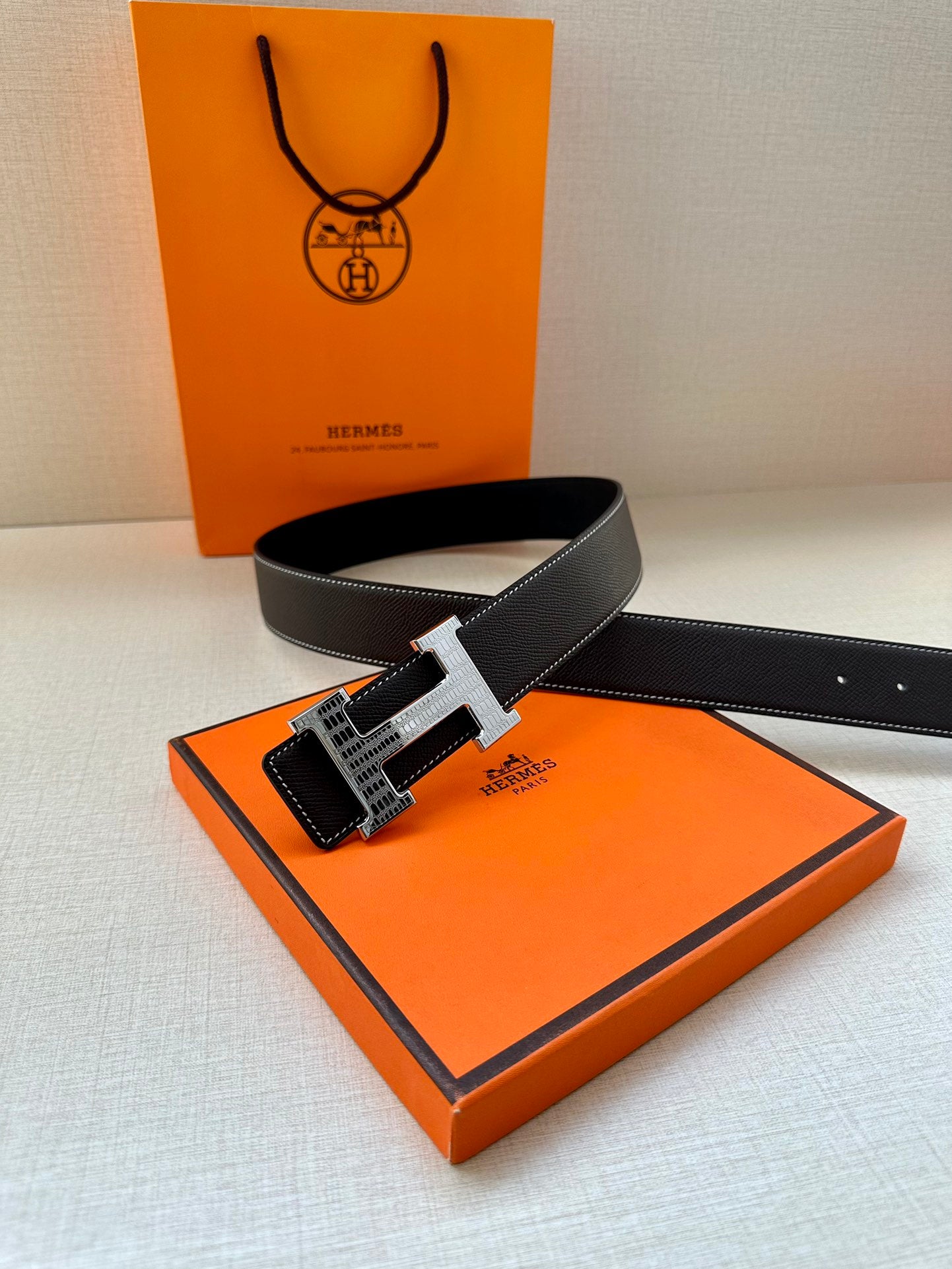 Dark leather belt with silver-tone buckle and textured strap holes