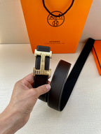 Dark leather belt with silver buckle and stitched edges, shown with tag