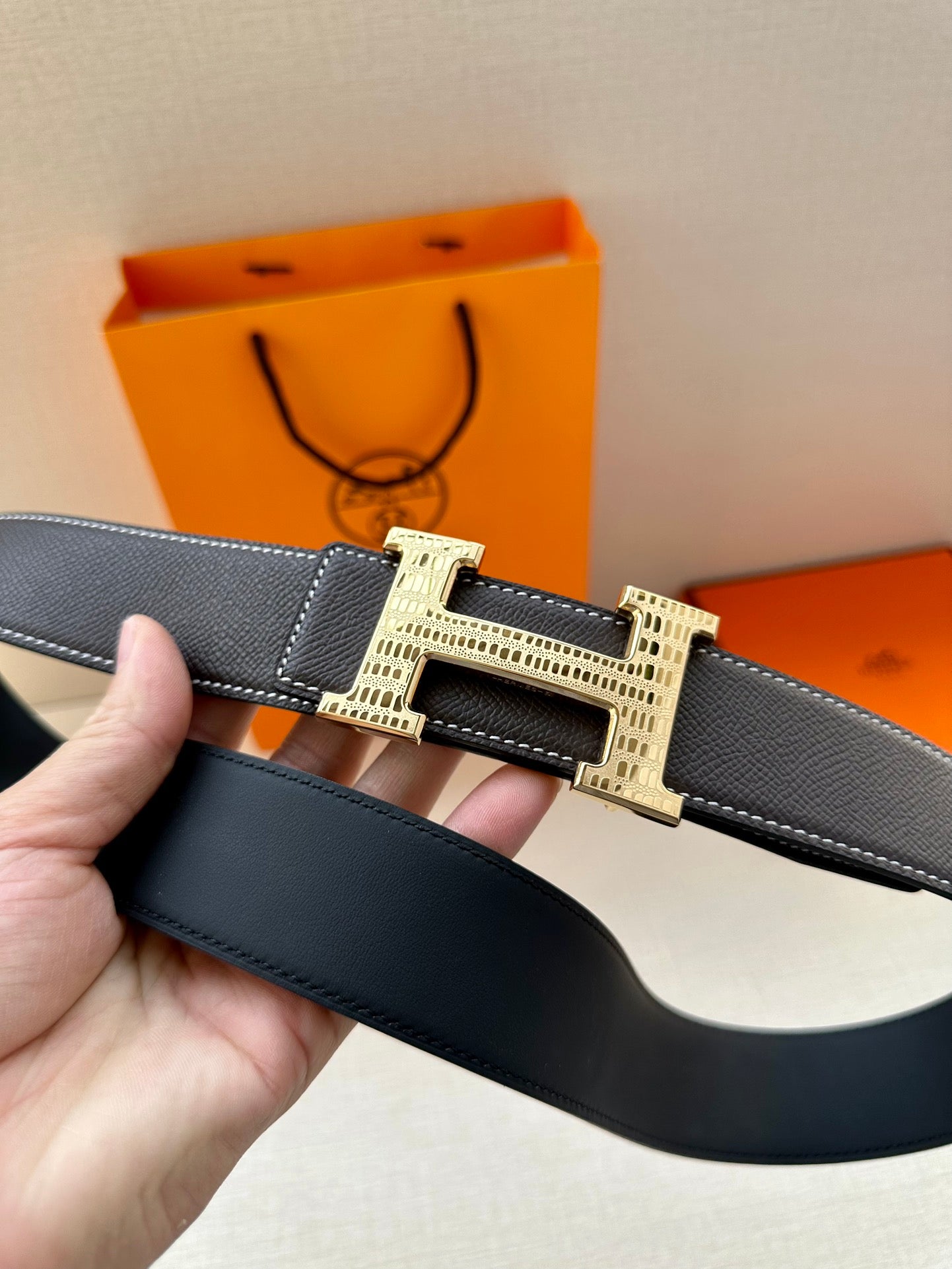 Dark leather belt close-up showing gold-tone buckle and wide strap