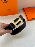 Dark leather belt with gold-tone buckle featuring embossed strap sections