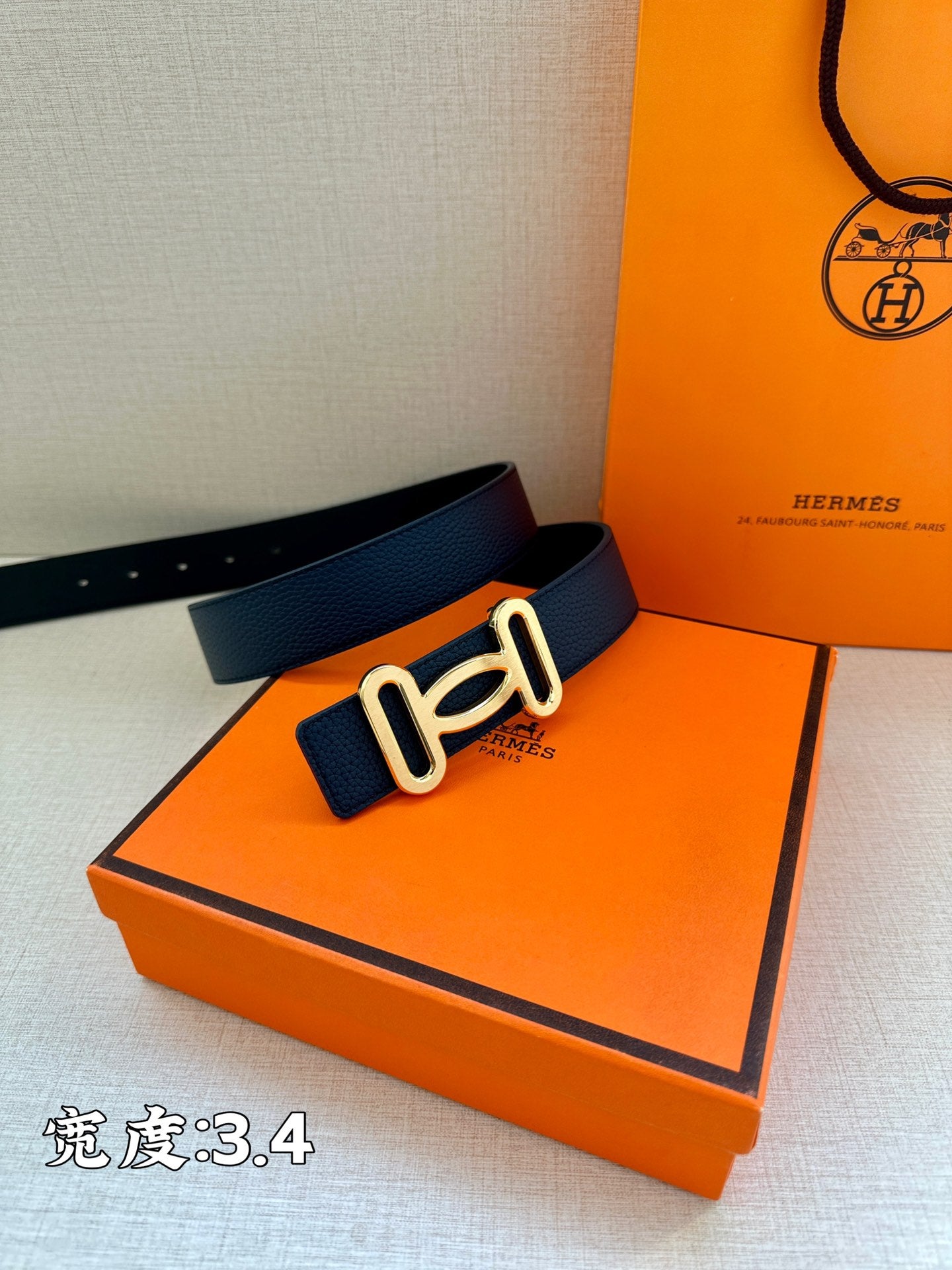 Navy leather belt with gold-tone double buckle on flat surface