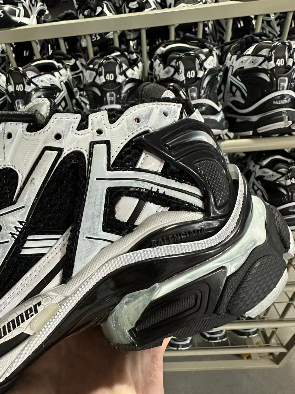 Close-up of black and white sneaker side with reflective trim and sculpted midsole.