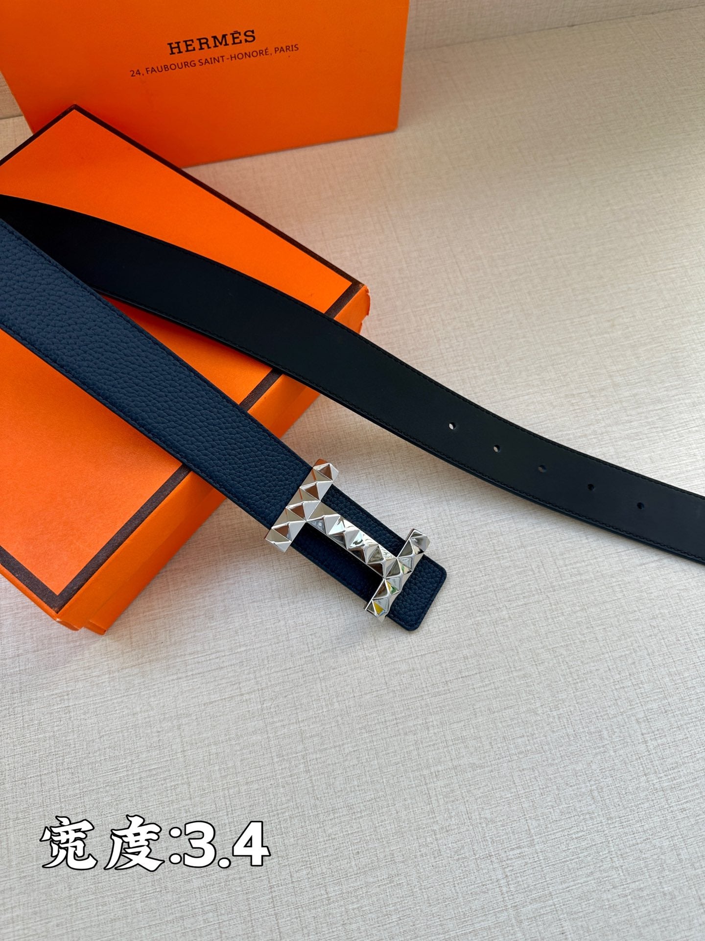 Hermes leather belt, dark blue strap with metallic studded buckle, side view