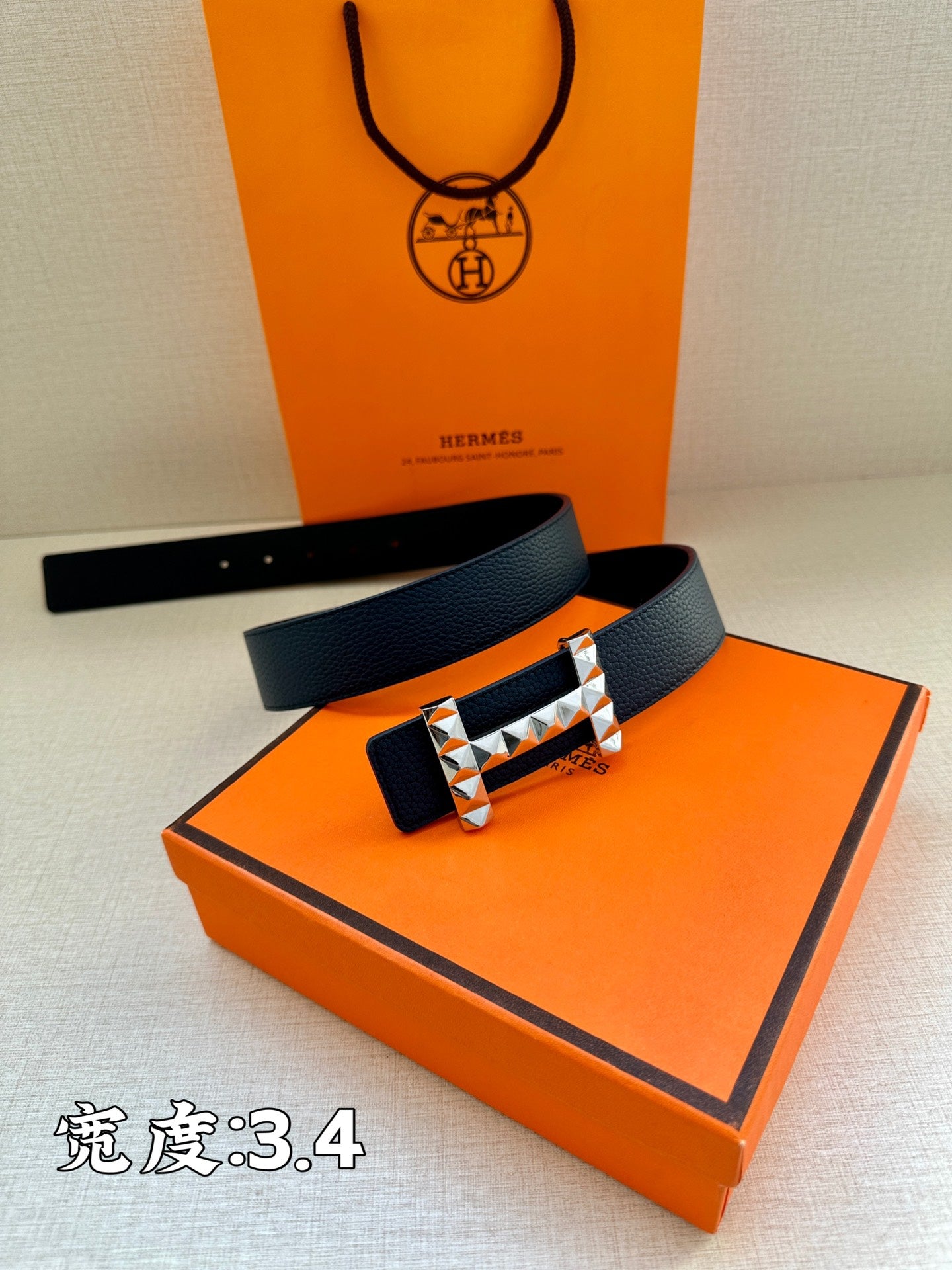 Hermes leather belt with dark blue strap and metallic studded buckle on box
