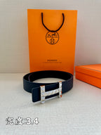Hermes leather belt with dark blue strap and metallic studded buckle, laid flat