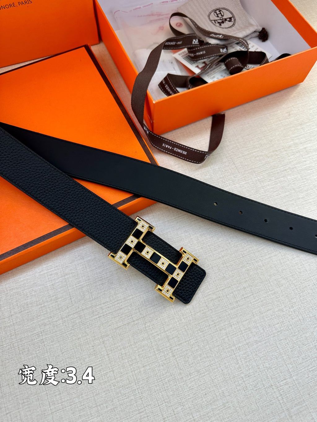 Dark leather belt strap with gold-tone rectangular buckle, laid flat for detail view.