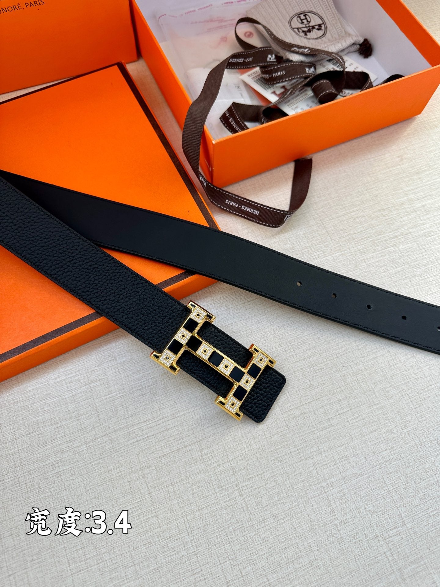 Dark leather belt strap with gold-tone rectangular buckle, laid flat for detail view.