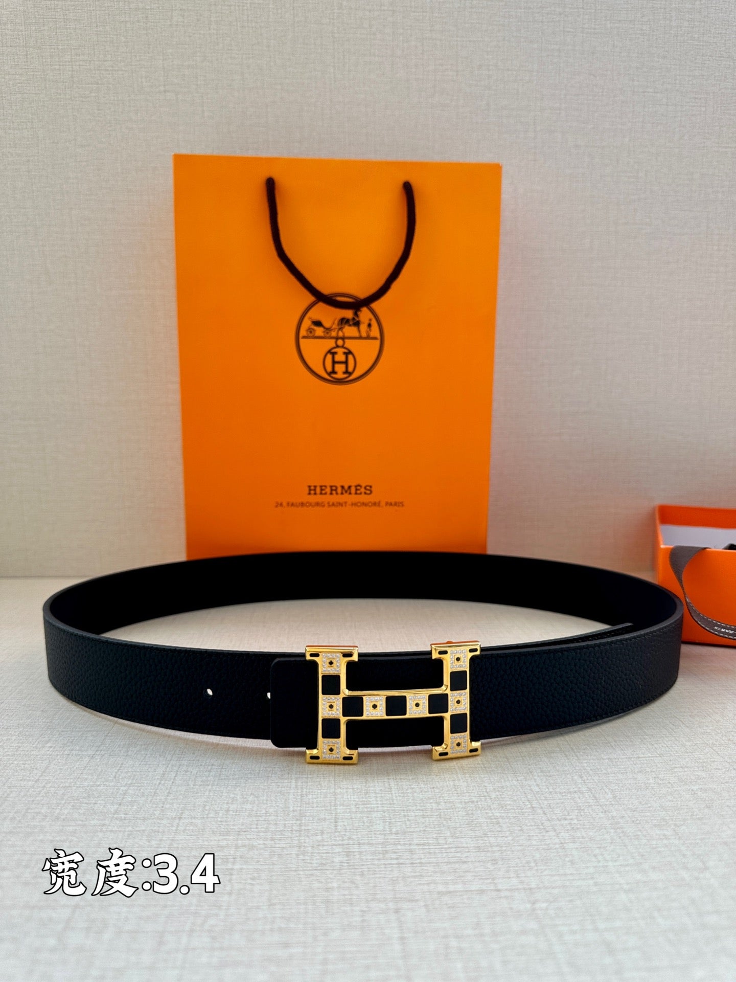 Dark leather belt with gold-tone square geometric buckle, laid flat.