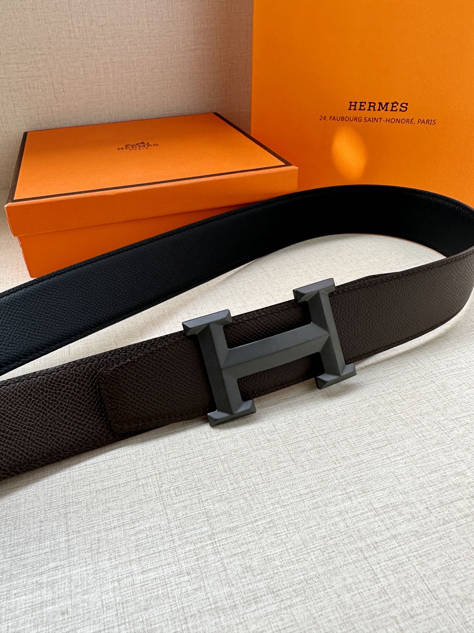 Leather belt with dark pebbled strap and rectangular H buckle; side view