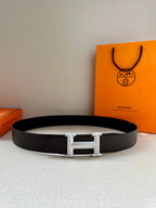 Leather belt with dark strap and silver-tone rectangular H buckle, lying flat