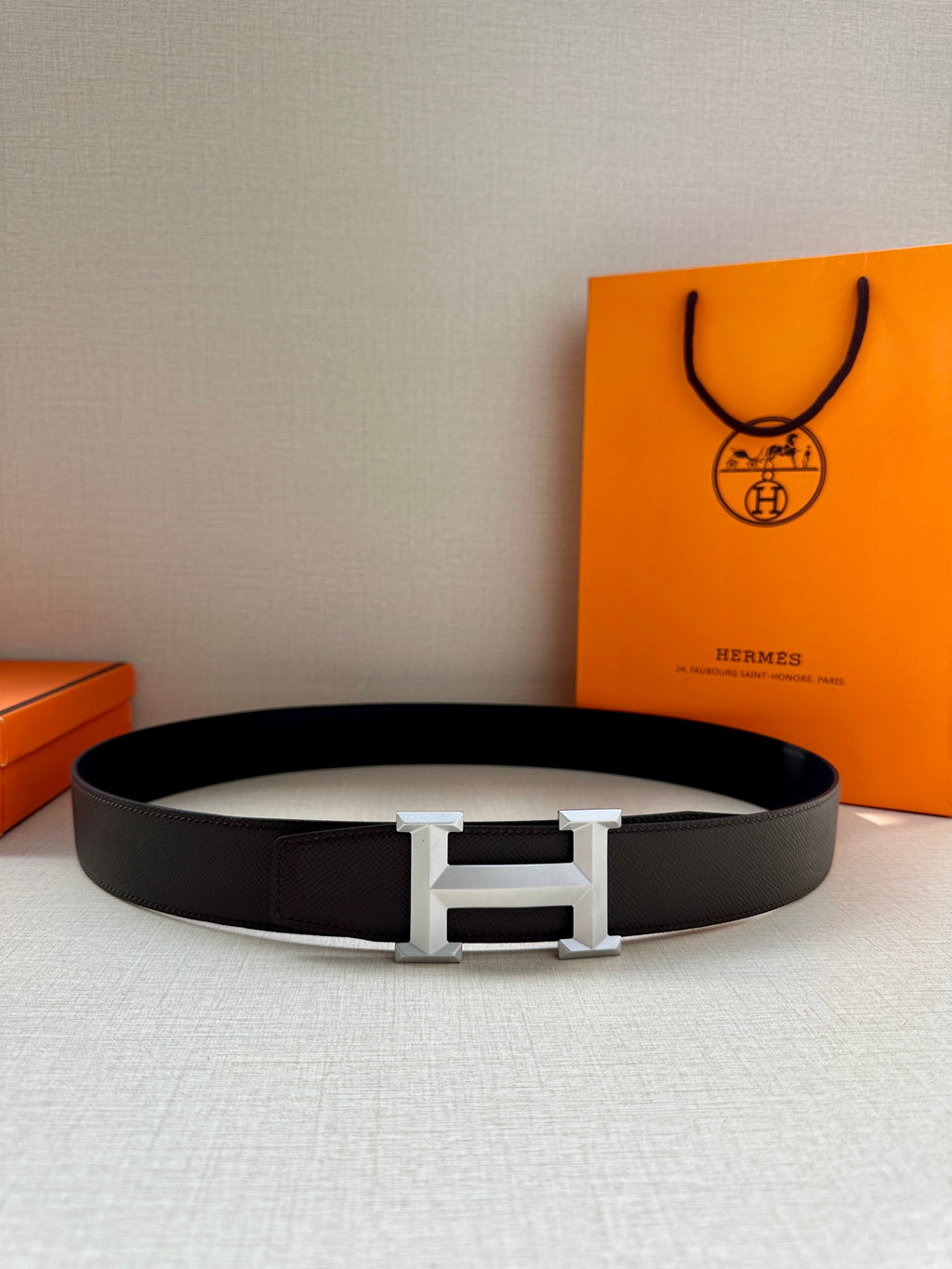 Hermes belt flat lay: black strap with silver H buckle