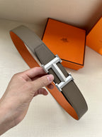 Hermes belt with textured leather strap and silver H-style buckle, worn by hand