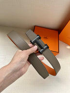 Hermes belt with gray strap and silver buckle, held up for side view
