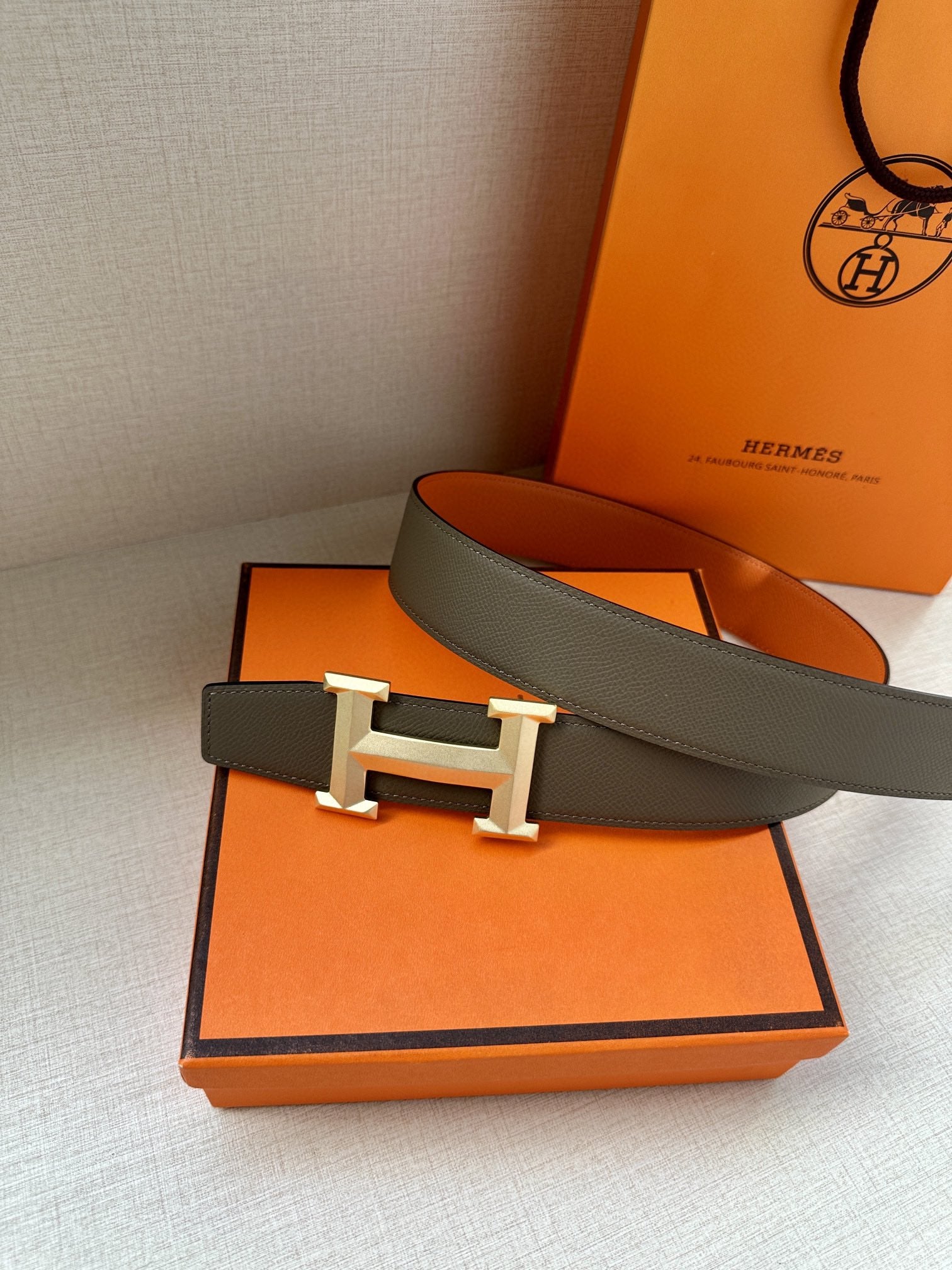 Hermes belt with gray strap, silver buckle, and orange reverse panel