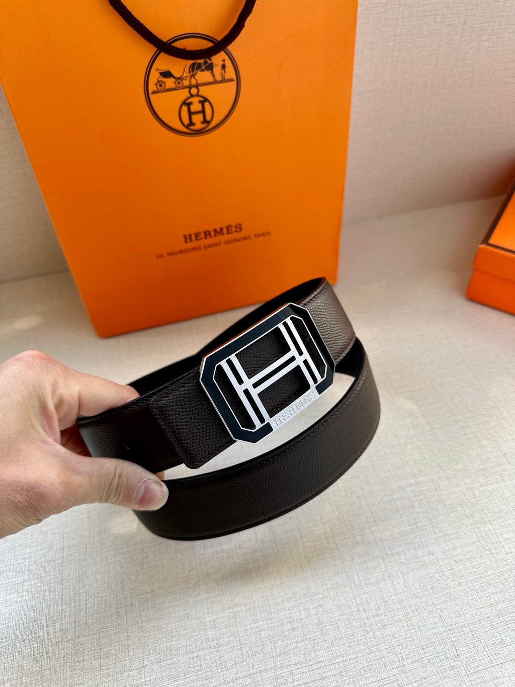 Dark leather belt with textured strap and silver buckle featuring mirrored H pattern
