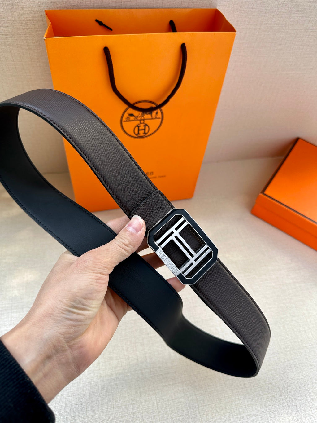 Dark leather belt with textured strap and silver geometric buckle in square frame
