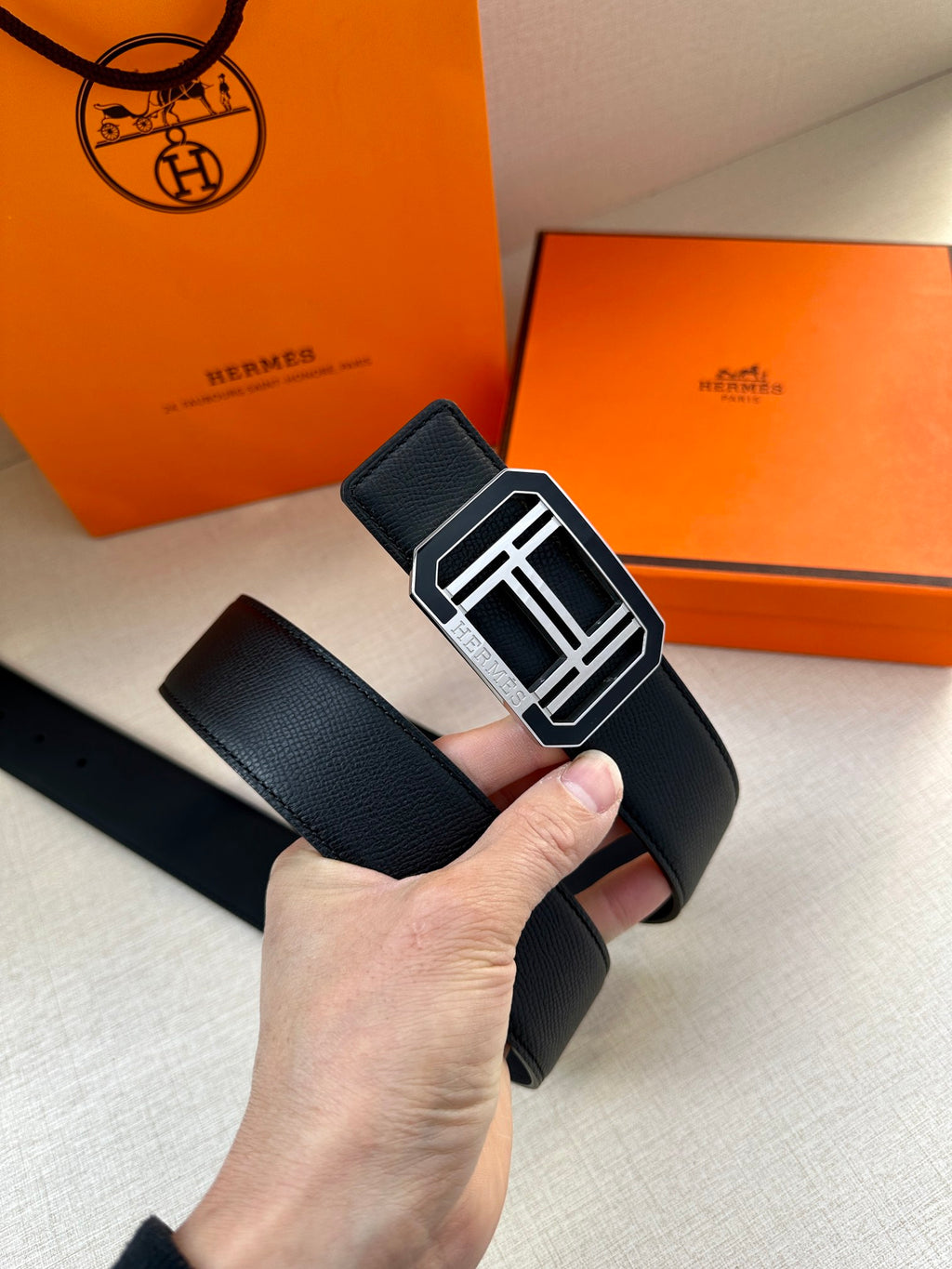 Hermes belt with dark leather strap and silver square F buckle, angled close-up