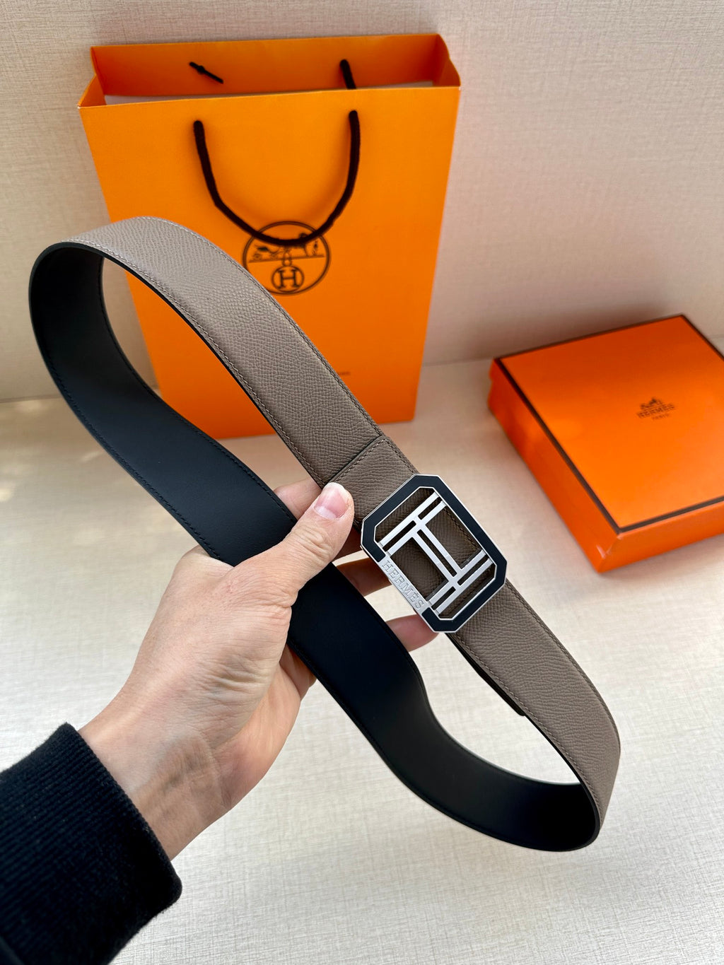 Gray leather belt with square silver buckle, angled view of the strap