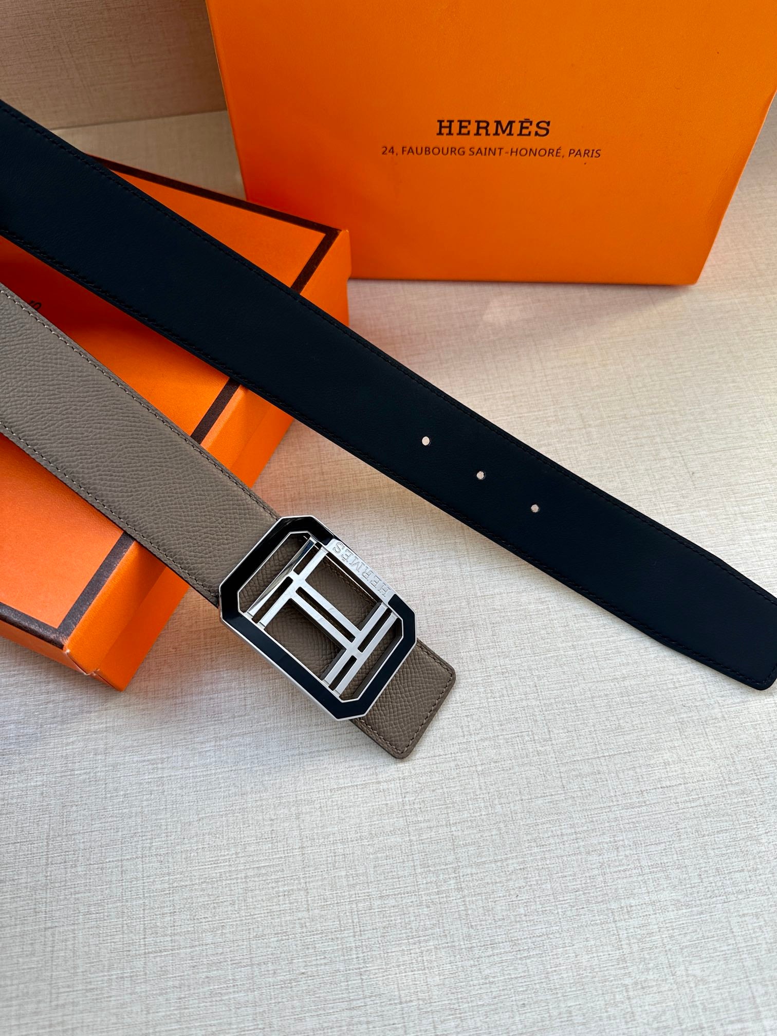 Gray leather belt with square silver buckle, laid flat on the surface
