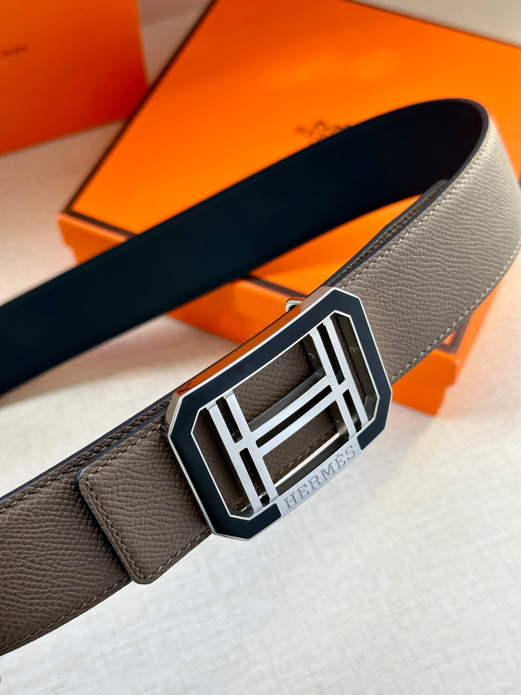Gray leather belt with square silver buckle, close-up on buckle front