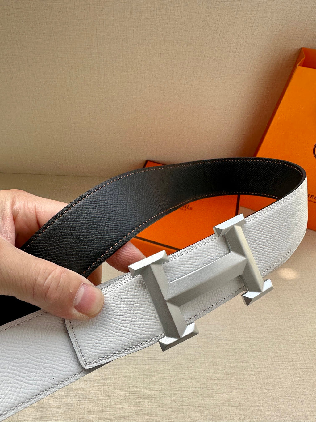 Leather belt with light gray and black reversible straps, silver-tone H buckle