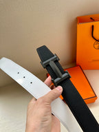 Leather belt with white and black sides, silver-tone H buckle close-up