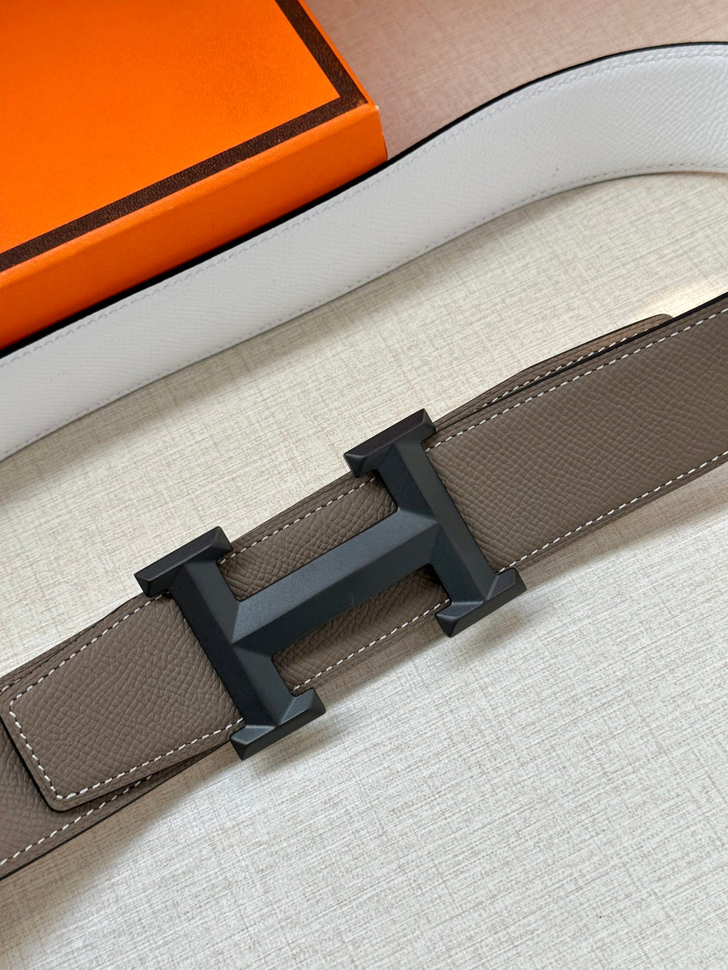 Hermes belt close-up: dark taupe leather strap with black-gray buckle bar and stitching