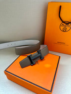 Hermes belt laid flat: taupe leather strap with black H buckle and leather keeper.