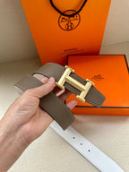 Hermes belt close-up: taupe leather with cream-tone H buckle and perforated holes.